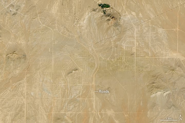 Satellite image of another part of California City: a web of straight and curving streets drawn across bare desert and low hills, with almost nothing built along them. NASA's label reads Roads; a scale bar shows one kilometre.