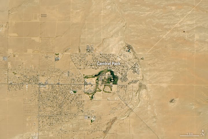 Satellite image of the built-up part of California City: blocks of houses around the green of Central Park and its lake, with bare desert crossed by straight roads around them. NASA's label reads Central Park; a scale bar shows one kilometre.